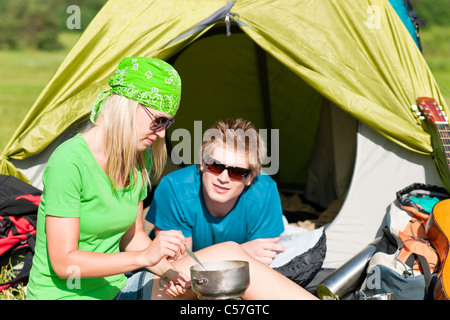 Camping Pärchen Kochen Mahlzeit im freien Zelt in sonniger Landschaft Stockfoto