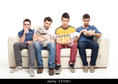traurig Gruppe junger Männer, die man auf einer Couch sitzend Fernsehen Stockfoto