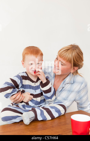 Mutter und Sohn im Schlafanzug am Tisch Stockfoto