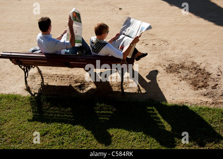 Paar sitzt auf einer Parkbank Zeitung lesen Stockfoto