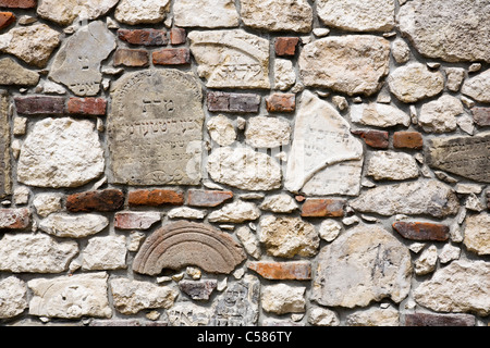 Fragmente der wiederhergestellten Grabsteine sind in eine Wand der Erinnerung auf dem neuen jüdischen Friedhof in Kazimierz, Krakau gemacht. Stockfoto