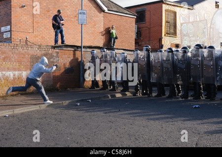 Randalierer wirft Ziegel Polizei Riot Steuerleitung Stockfoto