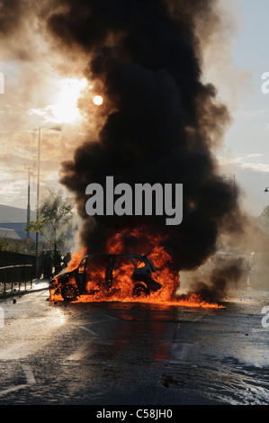 Ein Auto in der Mitte einer Straße mit viel schwarzen Rauch brennt Stockfoto