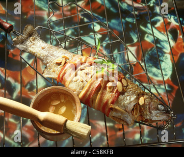 Gegrillte Forelle, umwickelt mit Speck mit Butter-, Mandel-Füllung Stockfoto