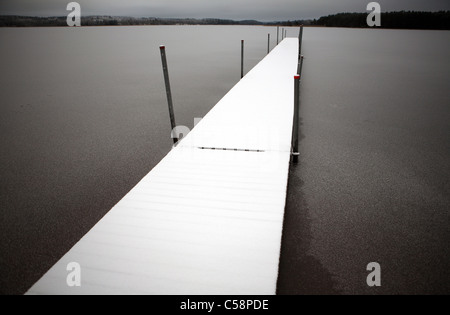 Ein Schnee-Cevered Steg erstreckt sich in einem See, Belloe, Schweden Stockfoto