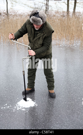 Ein Mann, der Bohrung eine Eis-Angeln im See Stora Bellen, Belloe, Schweden Stockfoto