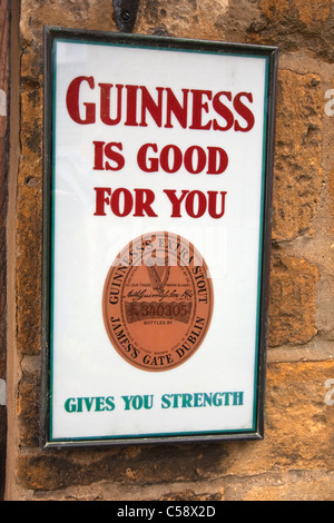 Guinness-Werbeschild an Wand vor Geschäft in Broadway, Worcestershire Stockfoto