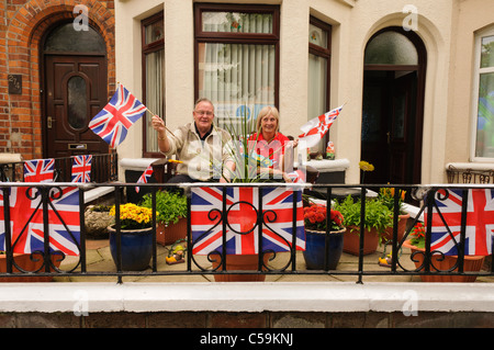 Zwei Personen wehende Fahnen in einem Garten an ein Straßenfest mit Union Jacks dekoriert. Stockfoto