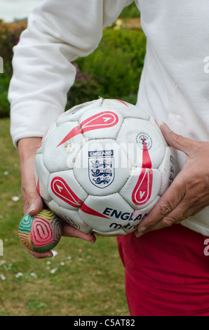 Eine England-Fußball und eine kleinere Kugel in einer Frauenhand gehalten Stockfoto