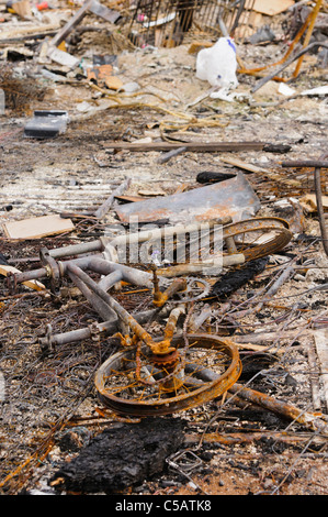 Verschiedene Objekte, darunter eine Fahrrad, das nach einem Brand in der Asche liegen. Stockfoto