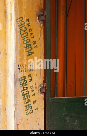 Telefonnummern auf einem ockerfarbenen Wand hängen Bong St, Altstadt in Hanoi, Vietnam Stockfoto