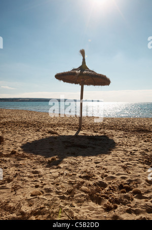 Leerer Strand mit strohgedeckten Sonnenschirm, Mallorca, Balearen, Spanien Stockfoto