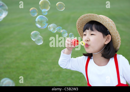 Mädchen bläst Seifenblasen durch einen Zauberstab Stockfoto