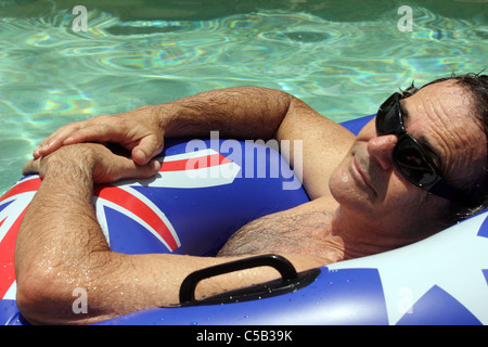 50 JAHRE ALTER MANN, SCHWIMMEN IN EINEM SCHWIMMBAD IN EINEM AUFBLASBAREN RING HORIZONTALE BDA Stockfoto