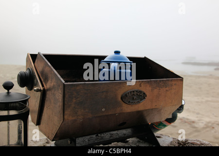 heißes Wasser für Kaffee und Tee an einem nebligen Morgen im Juli auf einem sandigen Strand camping zu machen Stockfoto
