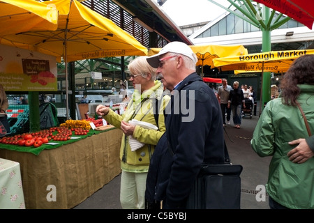 Ein älteres Ehepaar, die Inspektion eines Tomaten-Stall an der Borough Market London Bridge, Großbritannien Stockfoto