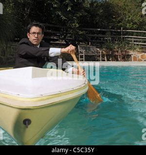 Gemischte Rassen Geschäftsmann Ruderboot im Schwimmbad Stockfoto