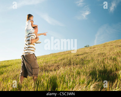 Vater mit Tochter auf Schultern im Feld Stockfoto