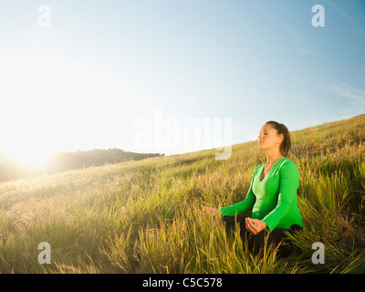 Hispanic schwangere praktizieren Yoga im Feld Stockfoto