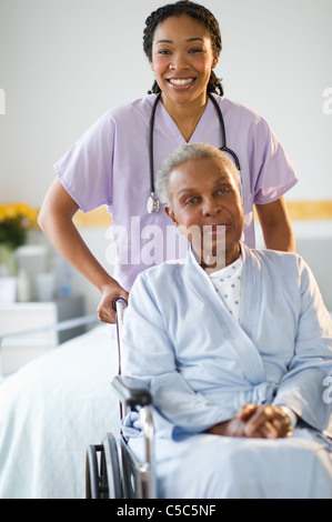 Krankenschwester drängen Frau sitzt im Rollstuhl im Krankenhaus Stockfoto