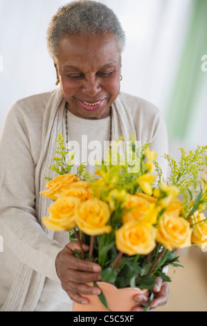 Schwarze Frau, die Vermittlung von Rosen in vase Stockfoto