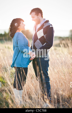 Schwangere Frau Mannes Händchenhalten im Feld Stockfoto