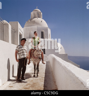 Mädchen auf Esel, hinunter zum Hafen geführt, auf der griechischen Insel Santorin, Kykladen, Ägäis, Griechenland Stockfoto