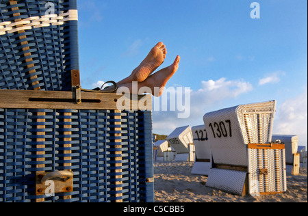 Füße heben sich aus überdachten Strandkorb auf Sylt, Nord-friesische Insel, Schleswig-Holstein, Deutschland Stockfoto