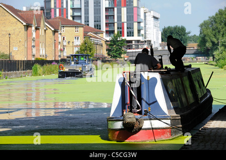 Nahaufnahme festgemacht Narrowboot auf der Lee Navigation mit britischen Wasserstraßen Maschine versucht, Sommer Algenblüte grünen Schleim zu schöpfen Hackney East London Großbritannien Stockfoto