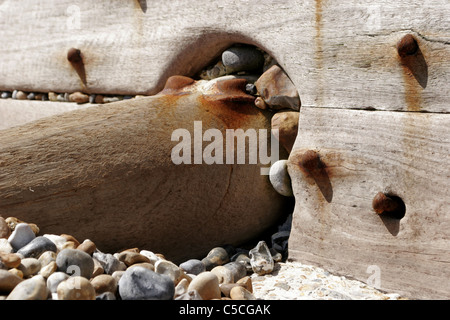 Bestandteil einer rostigen Wellenbrecher Meer Buhne zeigt Holzkonstruktion Schrauben und rostige Metall Befestigungen umgeben von Kiesel Stockfoto