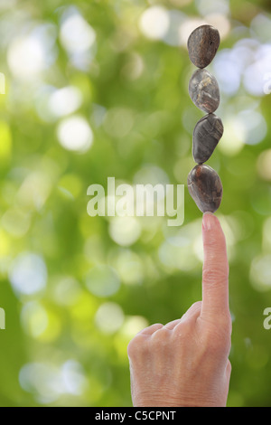 Hand Balance Steinen am Finger mit unscharfen Hintergrund Stockfoto