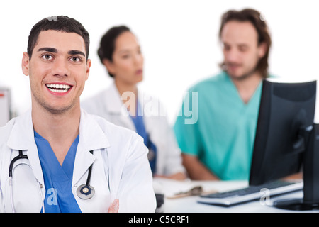 Glückliche junge Ärztin im Fokus, zwei andere in in weißem Hintergrund unscharf Stockfoto