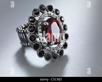 Nahaufnahme von einem Ring mit rotem Stein. Schmuck auf grauem Hintergrund isoliert. Stockfoto