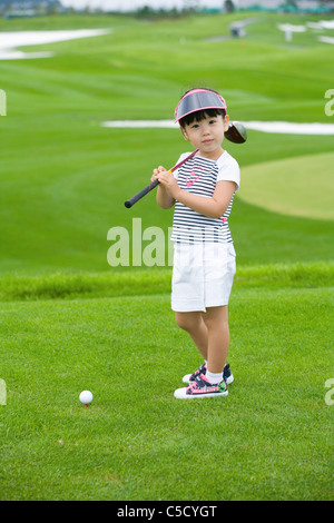 Mädchen hält Golf Eisen auf dem Feld Stockfoto