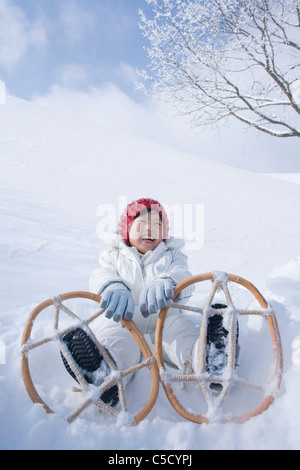 Mädchen sitzen tragen Schneeschuhe Stockfoto