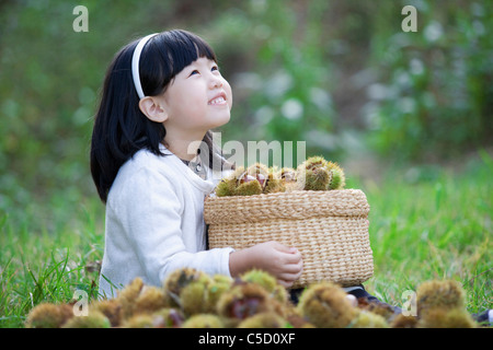 Mädchen umarmt Korb, voller Kastanien war Stockfoto