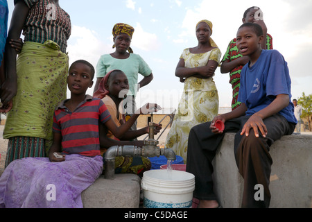 Tansania Dorf von Mwamalasa, Shinyanga. Sammeln von Wasser aus einem Vorratsbehälter. Das Wasser wird von Windmühlen in den Tank gepumpt. Stockfoto