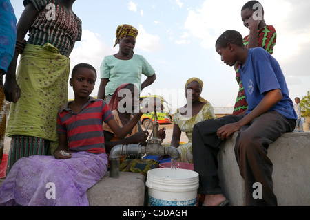 Tansania Dorf von Mwamalasa, Shinyanga. Sammeln von Wasser aus einem Vorratsbehälter. Das Wasser wird von Windmühlen in den Tank gepumpt. Stockfoto