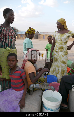 Tansania Dorf von Mwamalasa, Shinyanga. Sammeln von Wasser aus einem Vorratsbehälter. Das Wasser wird von Windmühlen in den Tank gepumpt. Stockfoto