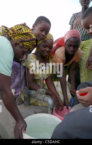 Tansania Dorf von Mwamalasa, Shinyanga. Sammeln von Wasser aus einem Vorratsbehälter. Das Wasser wird von Windmühlen in den Tank gepumpt. Stockfoto