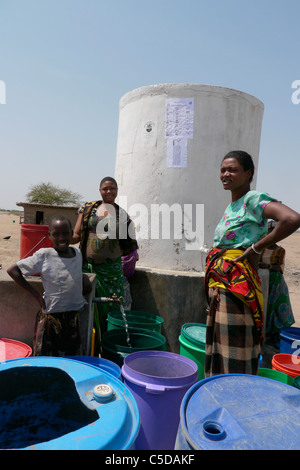 Tansania Dorf von Mwamalasa, Shinyanga. Sammeln von Wasser aus einem Vorratsbehälter. Das Wasser wird von Windmühlen in den Tank gepumpt. Stockfoto