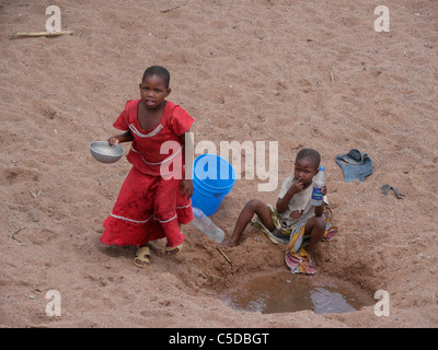 Tansania-Kinder sammeln von Wasser aus einem ausgetrockneten Fluss Bett in der Nähe von Shinyanga. Foto von Sean Sprague Stockfoto