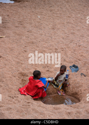 Tansania-Kinder sammeln von Wasser aus einem ausgetrockneten Fluss Bett in der Nähe von Shinyanga. Foto von Sean Sprague Stockfoto