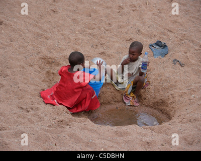 Tansania-Kinder sammeln von Wasser aus einem ausgetrockneten Fluss Bett in der Nähe von Shinyanga. Foto von Sean Sprague Stockfoto