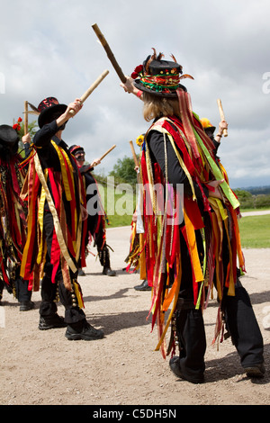 Schwarze Morris-Volkstänzer, zerrissene Kleidung. Menschen mit orangefarbenen, schwarzen und gelben Stoffstreifen im Tutbury Castle Weekend of Dance, Derbyshire, Großbritannien Stockfoto