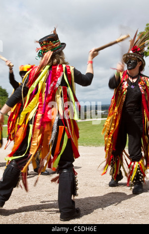 Schwarze Morris-Volkstänzer, zerrissene Kleidung. Menschen mit orangefarbenen, schwarzen und gelben Stoffstreifen im Tutbury Castle Weekend of Dance, Derbyshire, Großbritannien Stockfoto