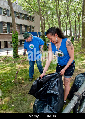 Uniformierte Sanitation Arbeiter, darunter eine tätowierte Frau sammeln Müll in Cadman Plaza, Brooklyn, NY. Stockfoto