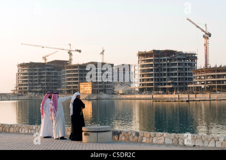 Elk204-1007 Bahrain, Manama, arabische Männer in traditioneller Kleidung betrachten Hochhaus Bau aus durch den Hafen Stockfoto