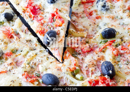 Pizza mit Mozzarella-Käse und frischen Tomaten und Pesto-Sauce. Garniert mit getrockneten Tomaten, grüne und schwarze Oliven und Basilikum Lea Stockfoto