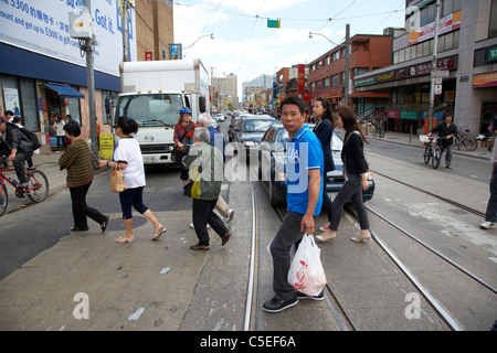 chinesische und asiatische Herkunft Menschen zu Fuß quer durch die Straße Kreuzung Innenstadt Chinatown Toronto Ontario Kanada Stockfoto